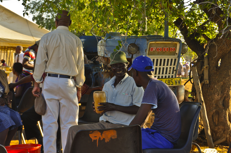 Under the tree by the tractor.